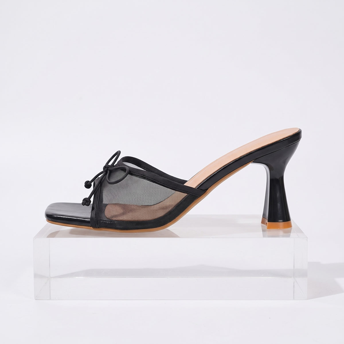 Side view of the black bow mule showing the stiletto heel