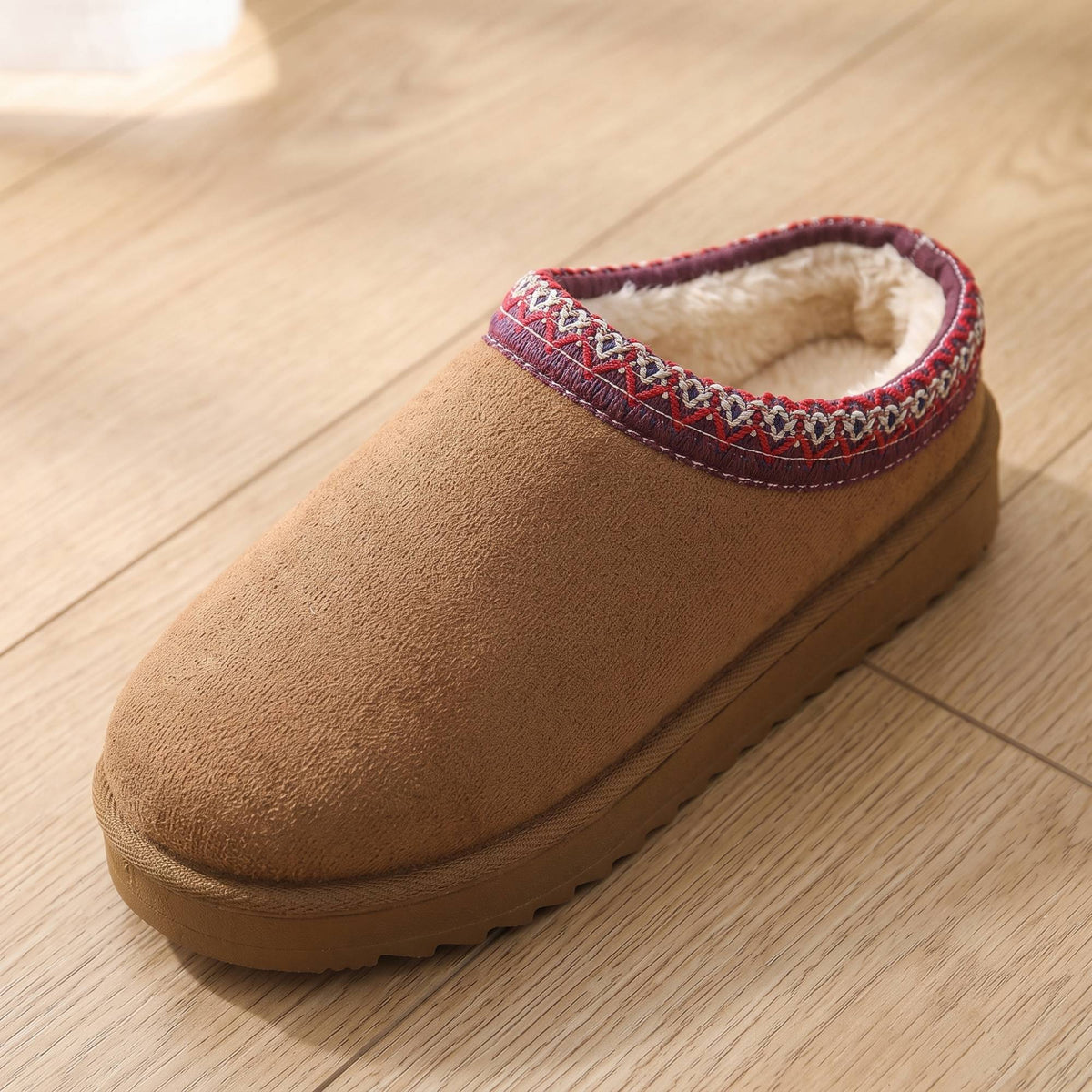 Close-up of the plush faux-fur lining and woven trim on a chestnut slipper